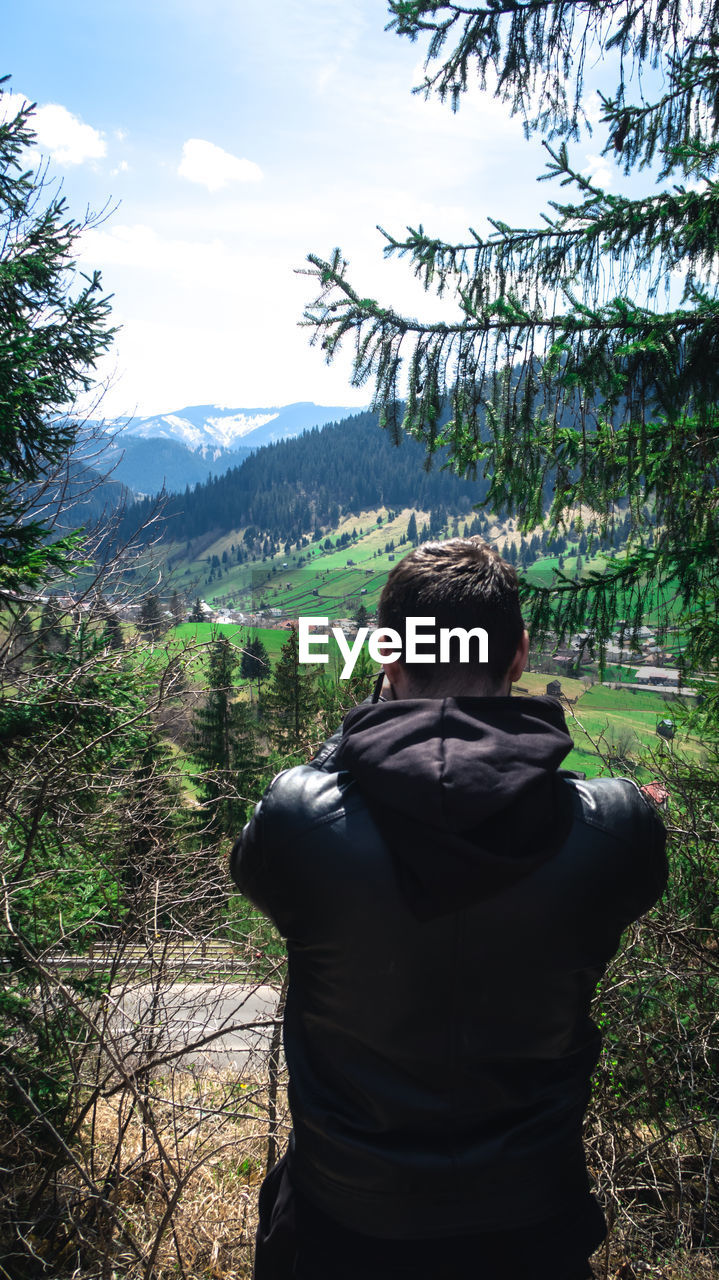 REAR VIEW OF MAN LOOKING AT MOUNTAINS