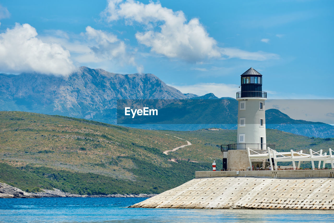 lighthouse by mountains against sky