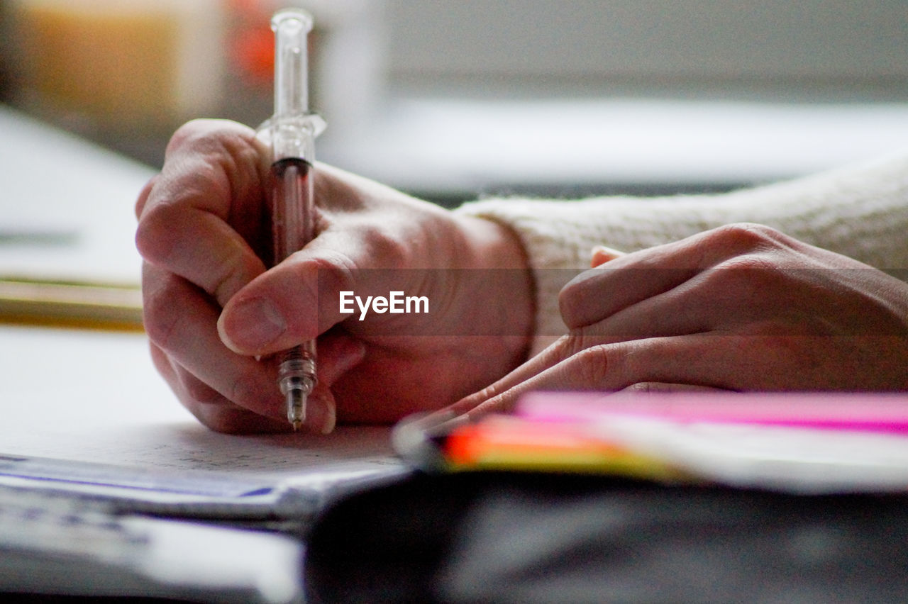 Cropped hands of person writing on book