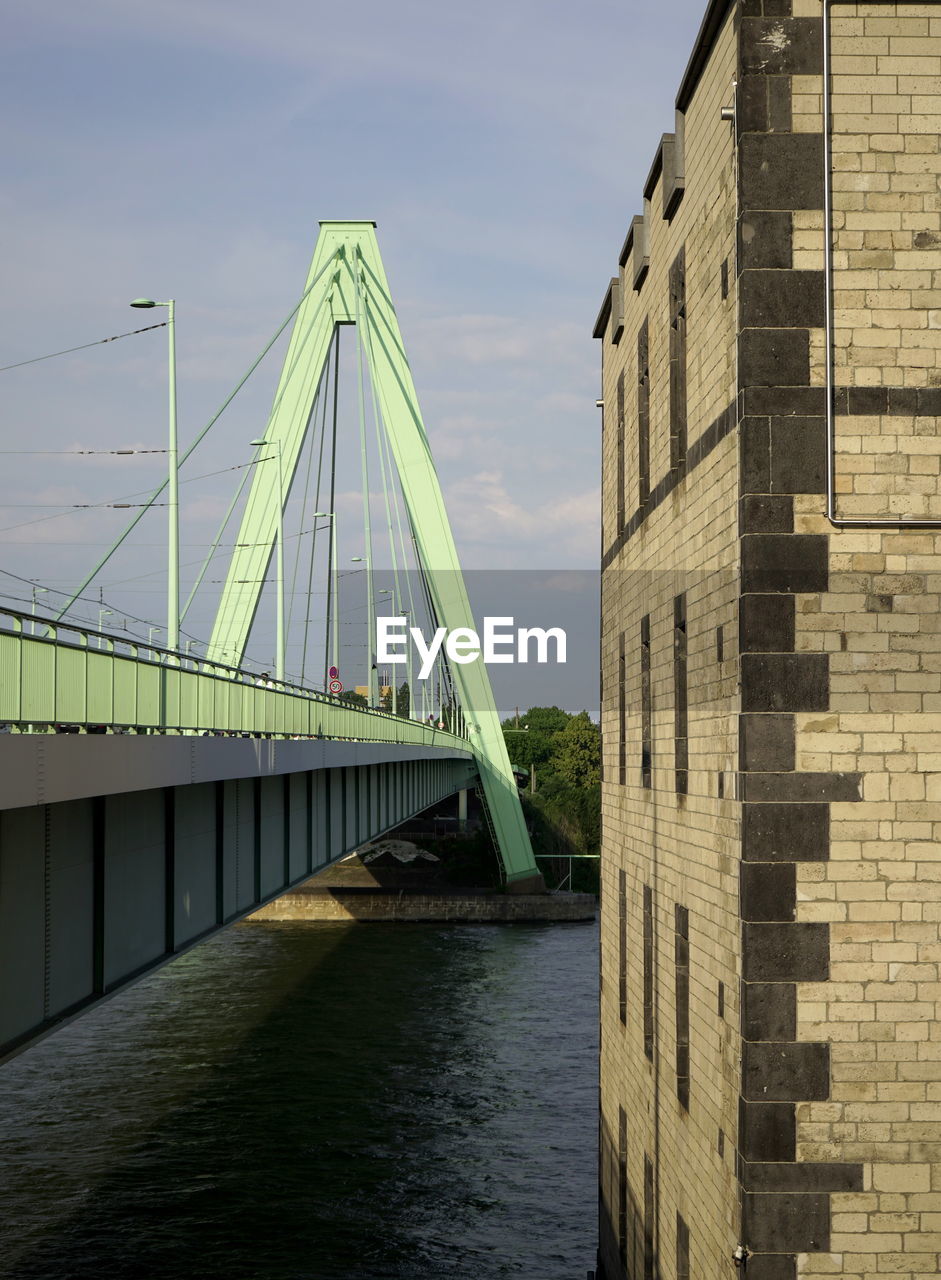 Bridge over river by buildings against sky