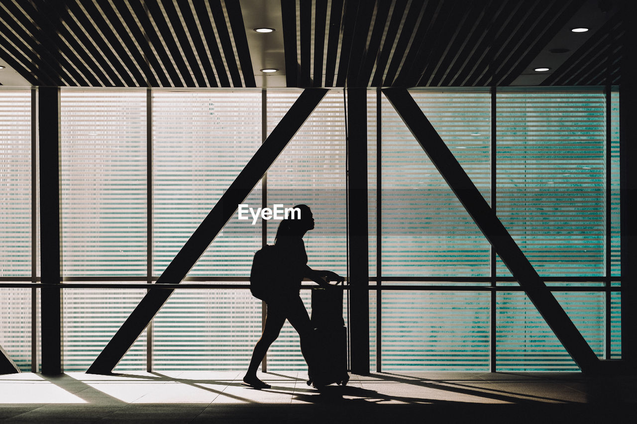 Side view of silhouette teenage girl walking at airport