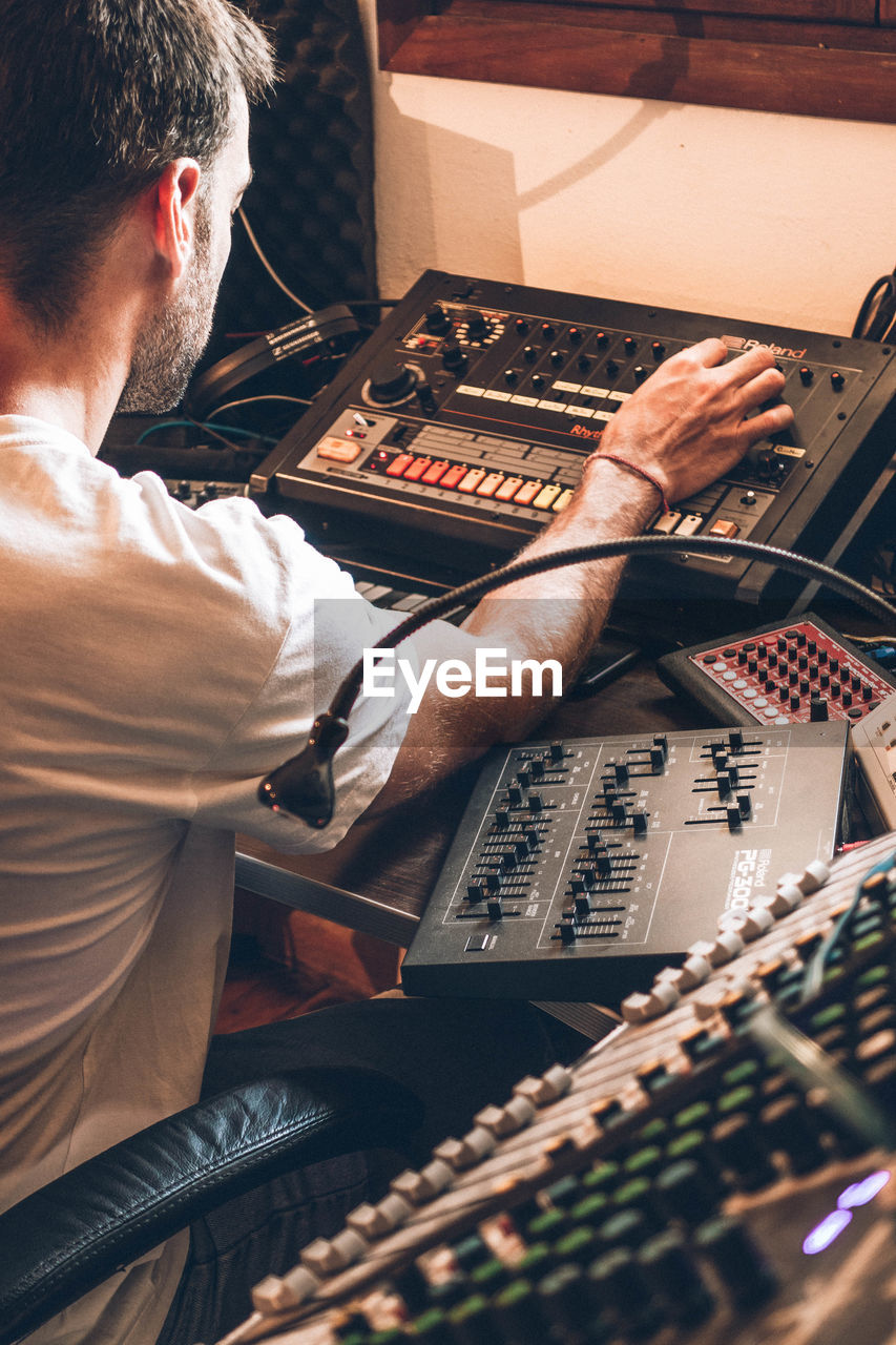 Man operating sound mixer while sitting at table