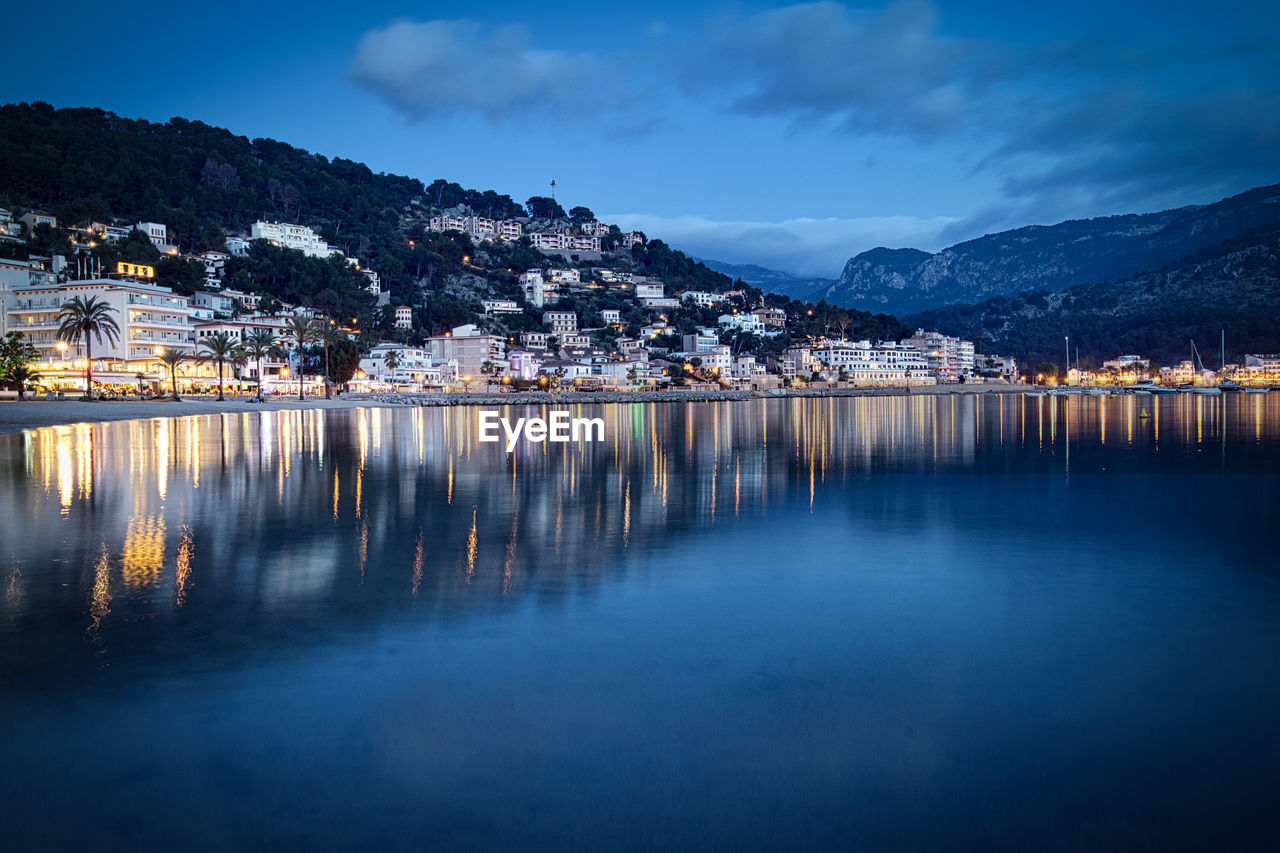 REFLECTION OF ILLUMINATED BUILDINGS IN LAKE AGAINST SKY