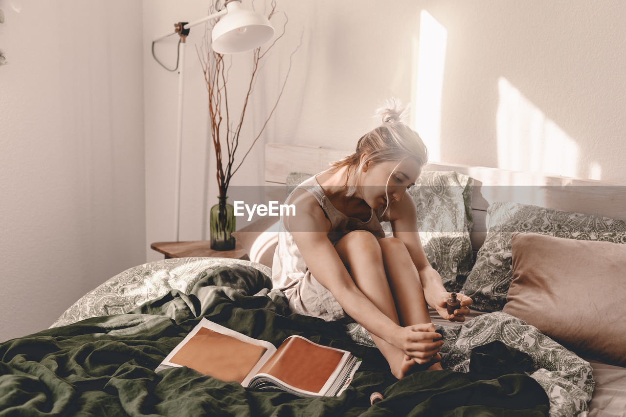 YOUNG WOMAN SITTING ON BED