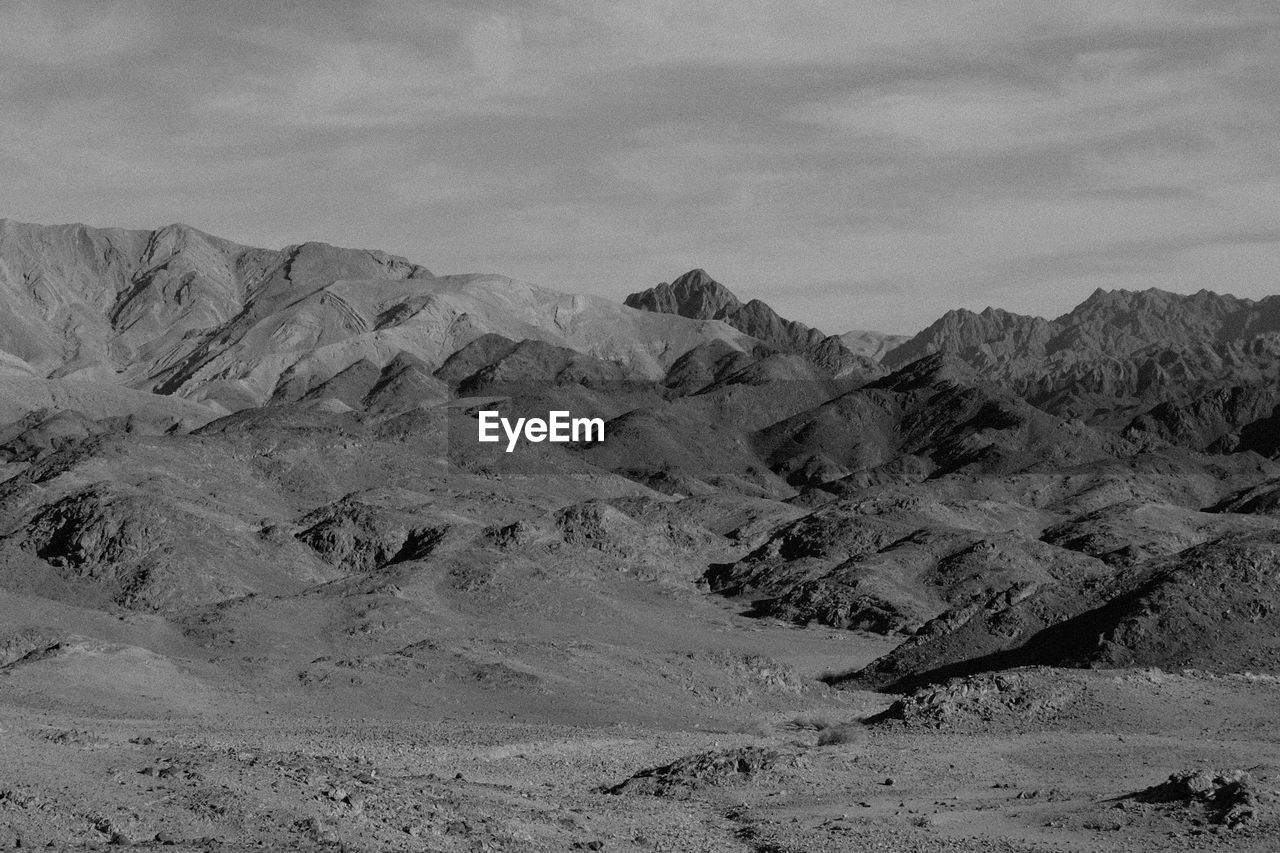 mountain, landscape, environment, scenics - nature, black and white, sky, nature, land, monochrome, monochrome photography, beauty in nature, desert, mountain range, no people, snow, cloud, non-urban scene, tranquility, plateau, tranquil scene, day, arid climate, outdoors, extreme terrain, rock, travel destinations, geology, travel, physical geography, remote, natural environment, climate