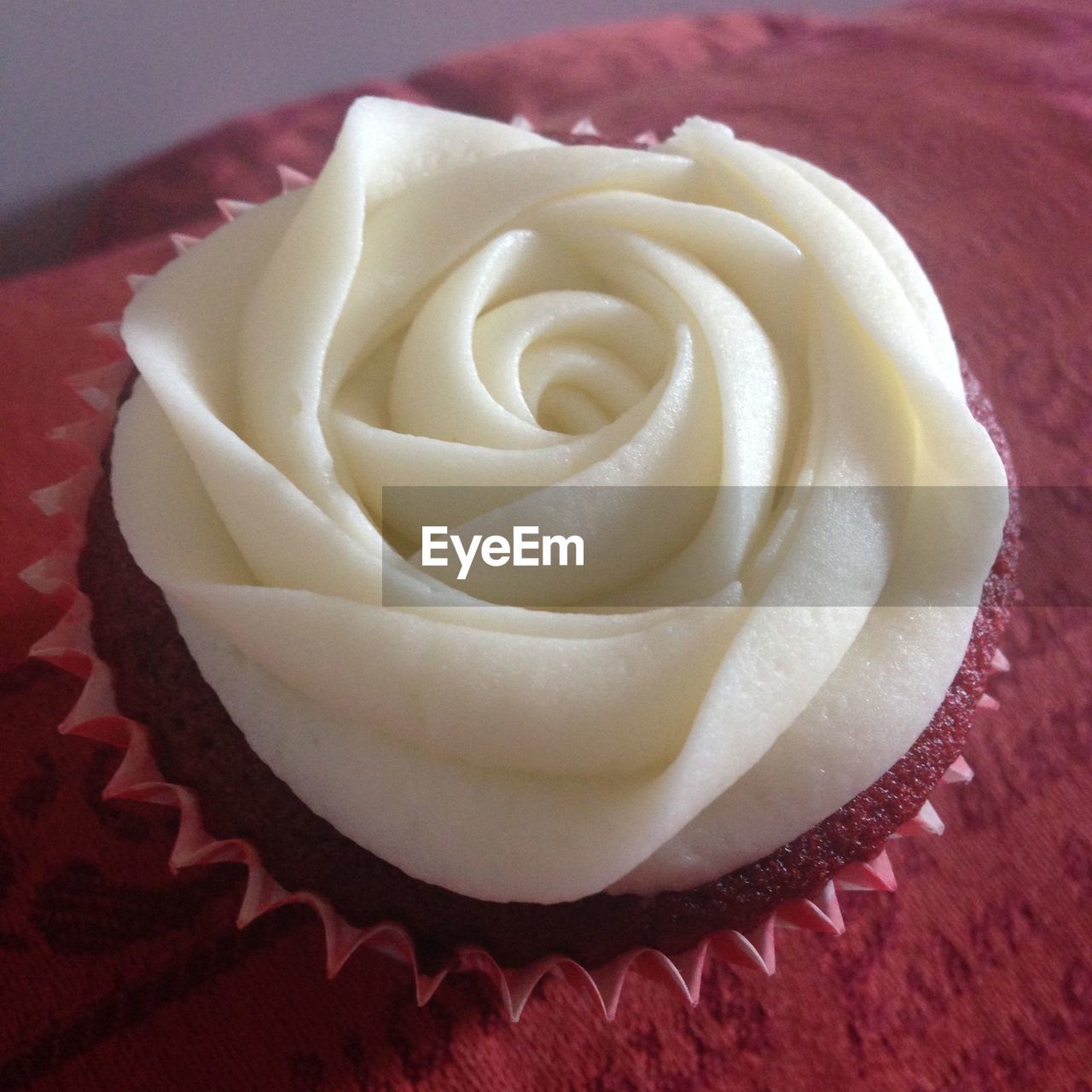 Close-up of frosting shaped in a rose on red velvet cupcake