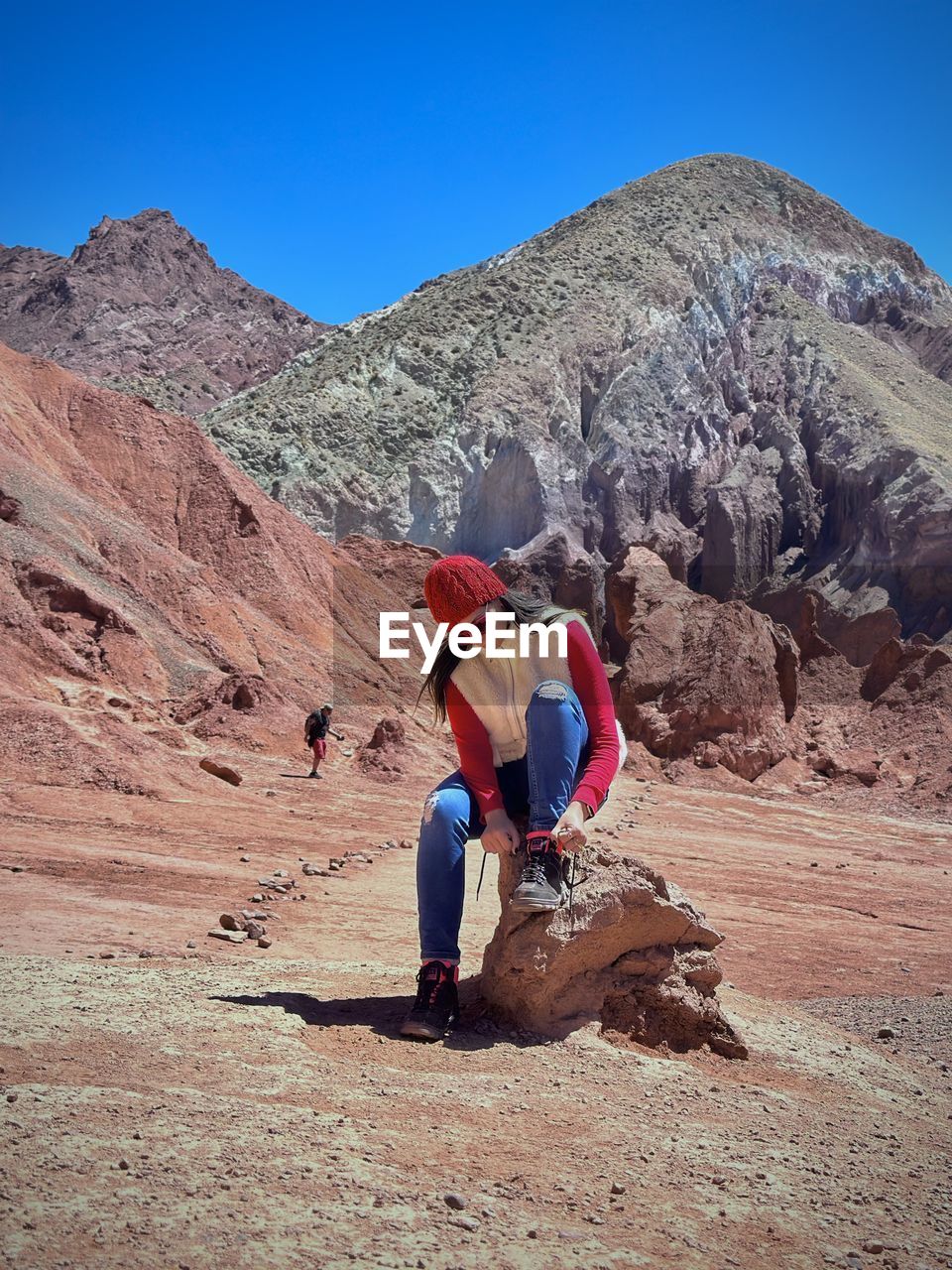 Side view of woman standing on mountain rock against clear blue sky