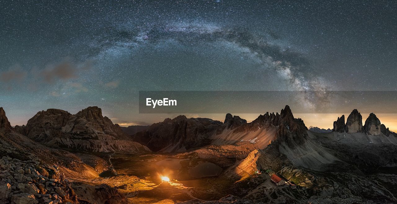 Scenic view of illuminated mountains against sky at dusk