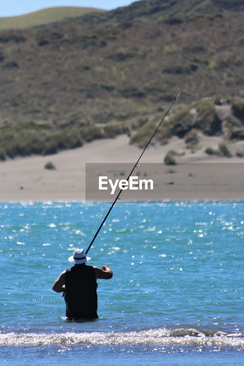 Rear view of man fishing in sea