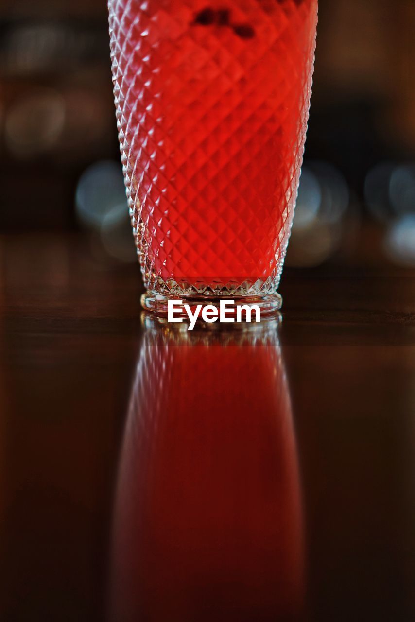 Close-up of red wine in glass reflecting on table