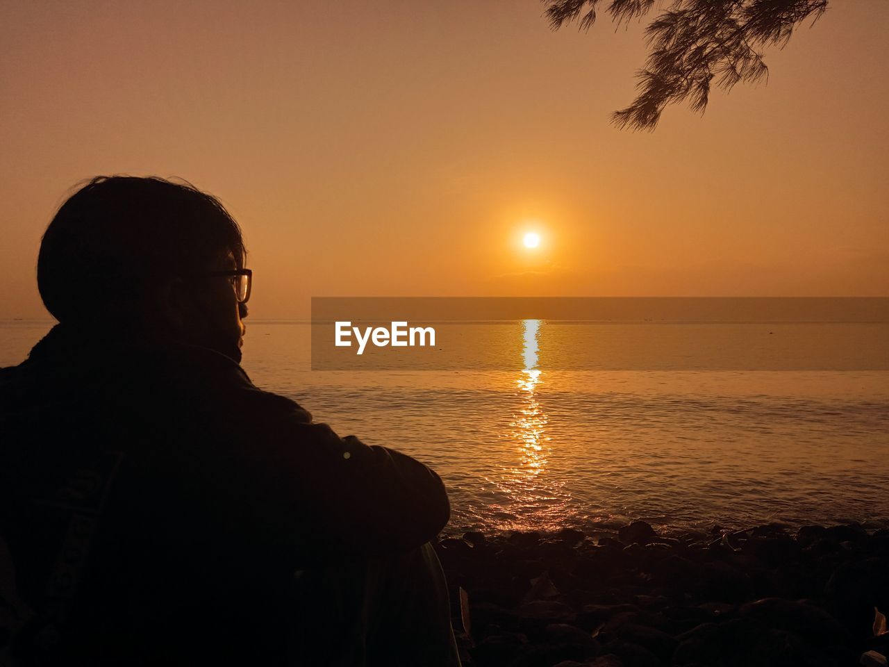 Silhouette man looking at sea against sky during sunset