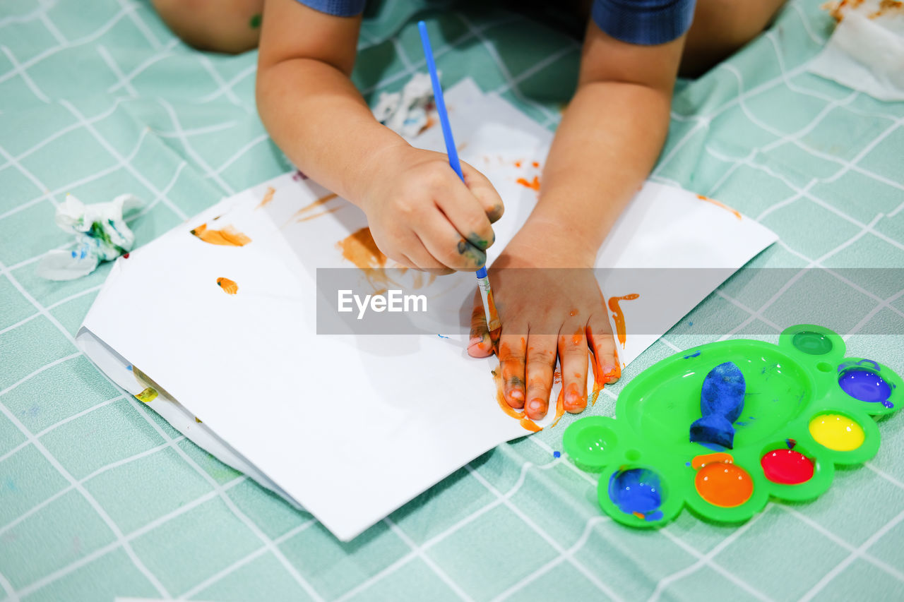 HIGH ANGLE VIEW OF GIRL PLAYING WITH PAPER ON TABLE