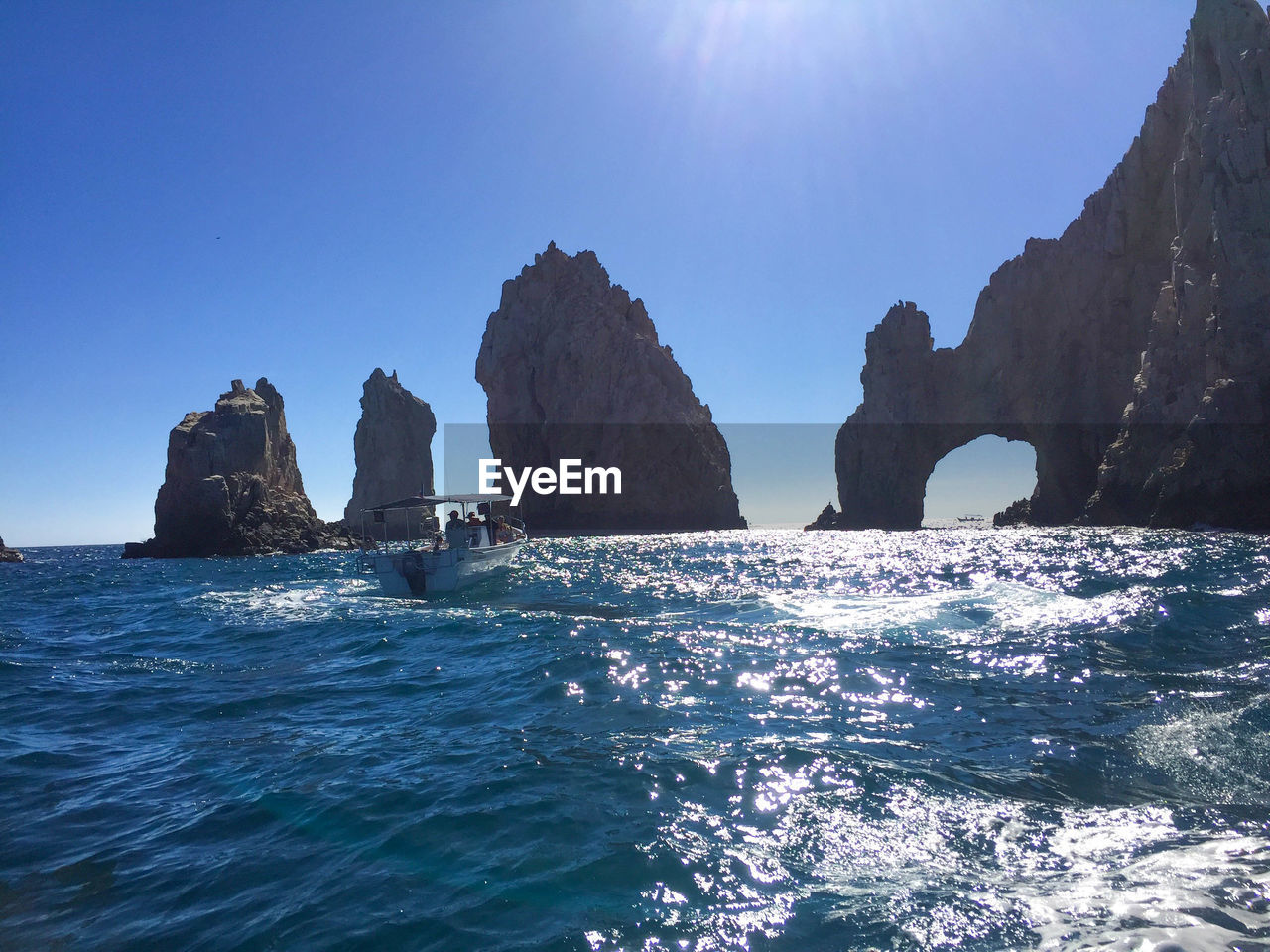 Rocks on sea against clear blue sky