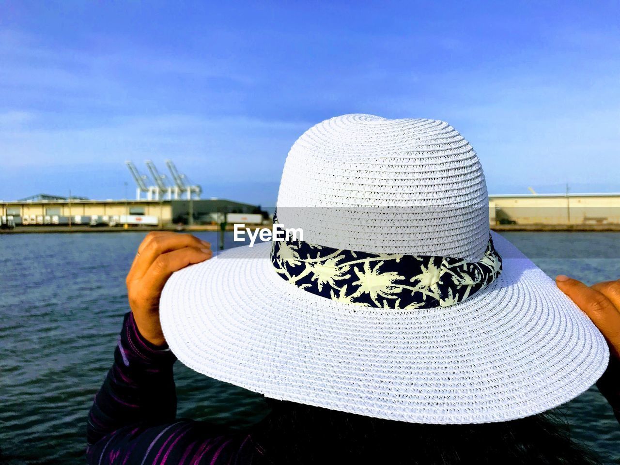 Rear view of woman holding hat against sea