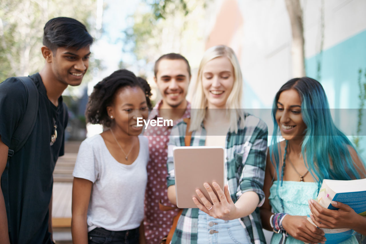 Cheerful friends using digital tablet