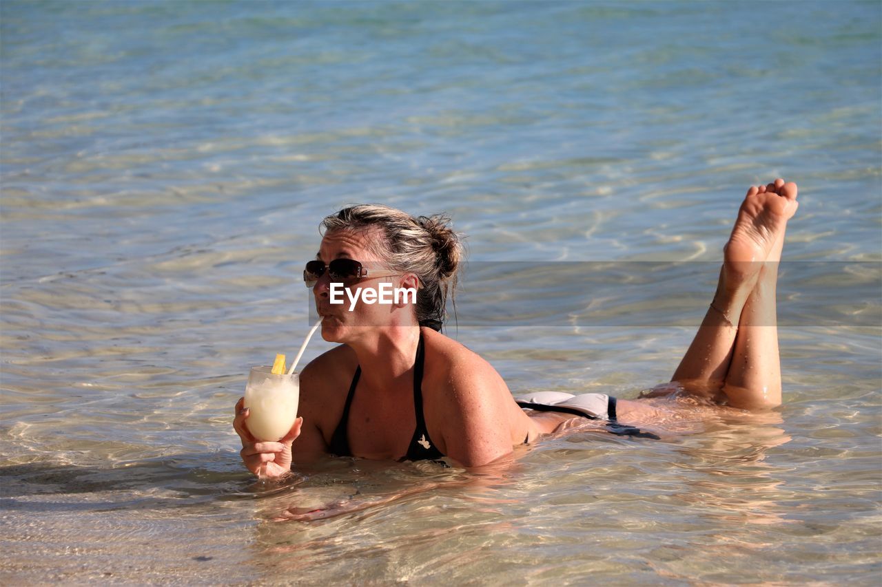 Woman having drink while relaxing at beach