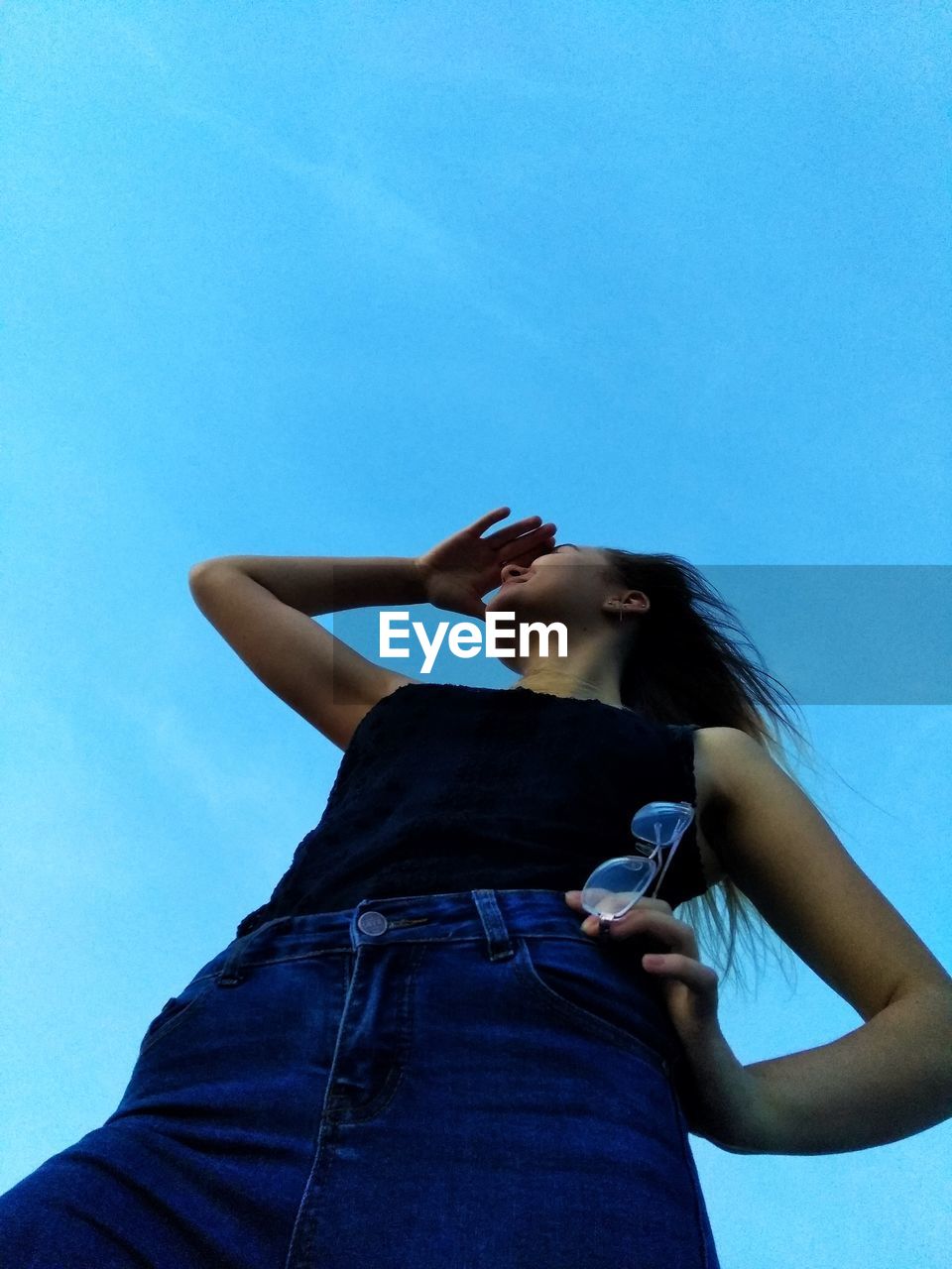 Low angle view of woman standing against blue sky