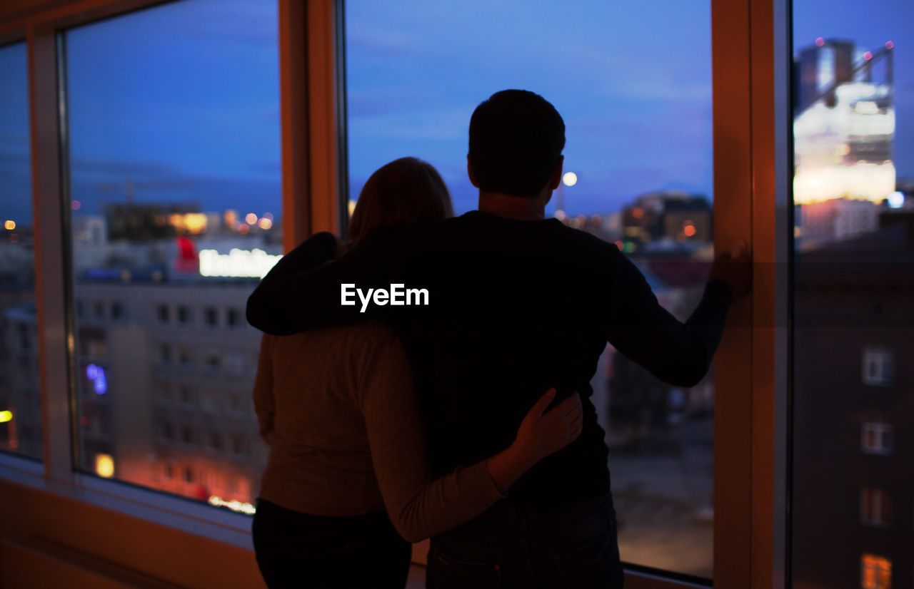 Silhouette of woman looking through window