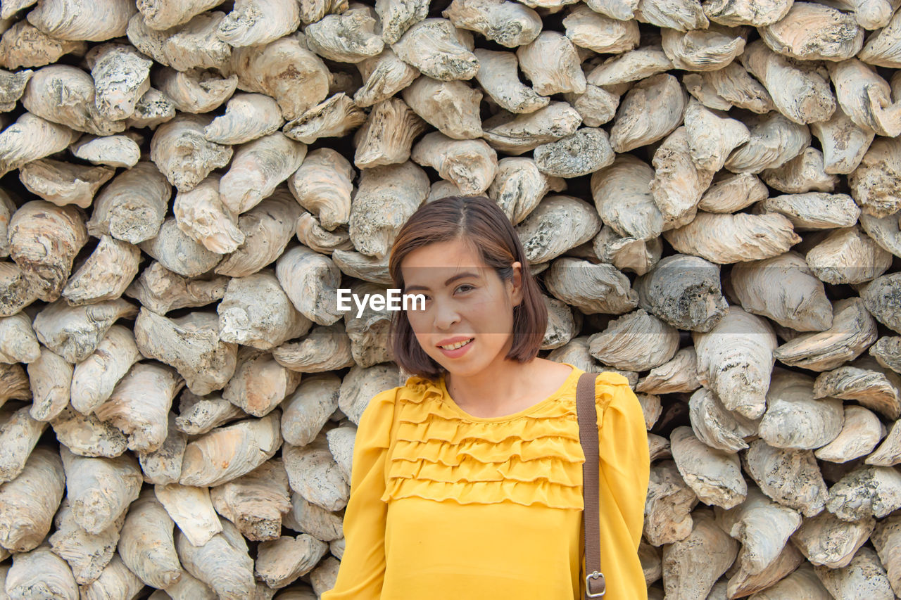 Portrait of woman standing against stone wall