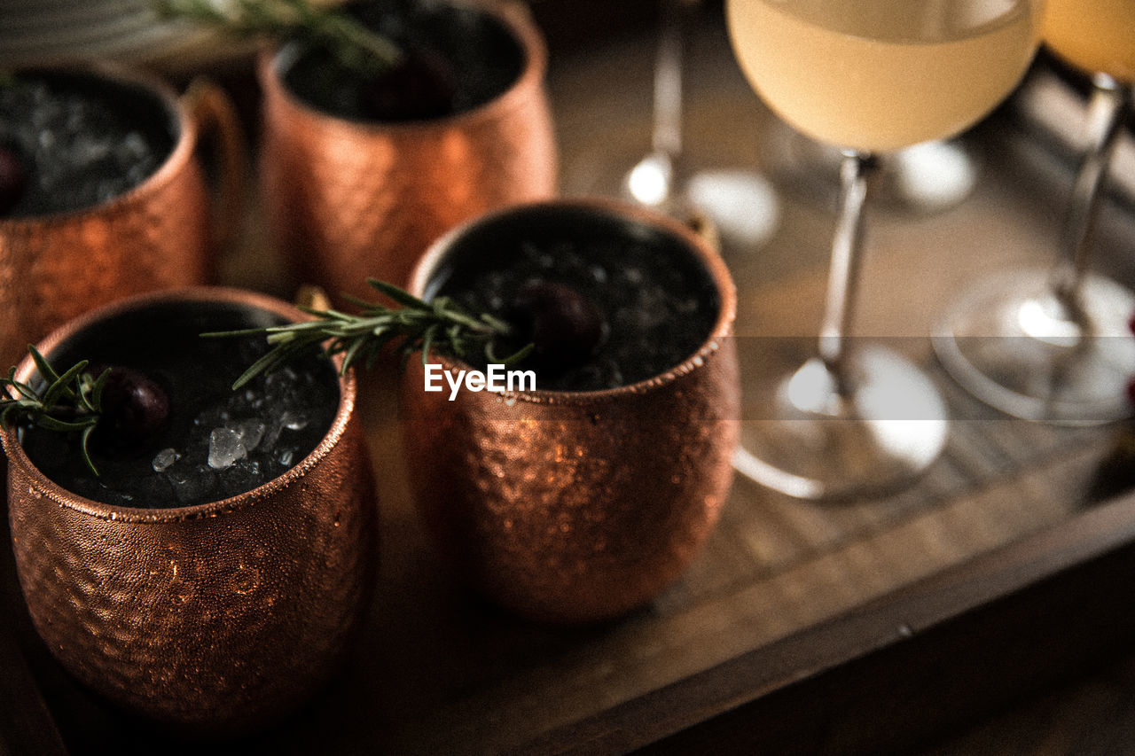 Copper mugs with rosemary sprigs and wine glasses arranged for celebration and entertaining guests 