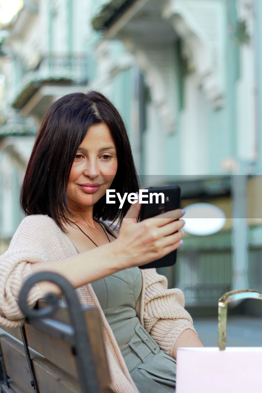 Young beautiful woman smiling going to the shops using mobile phone