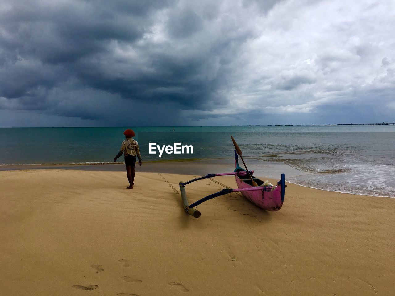 Man standing on beach against cloudy sky