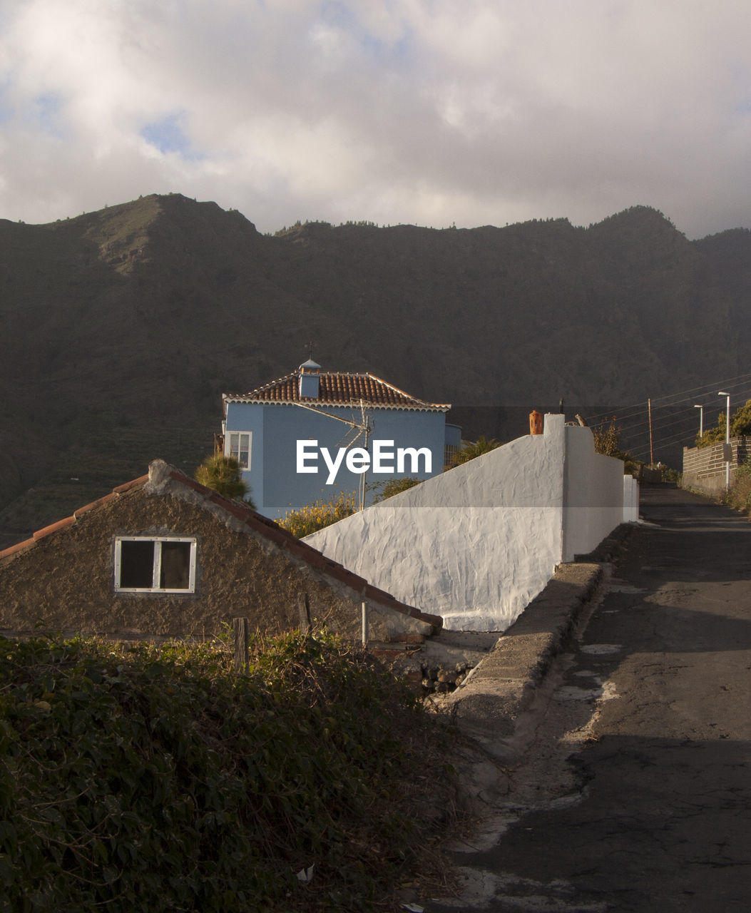 HOUSES BY BUILDINGS AGAINST SKY