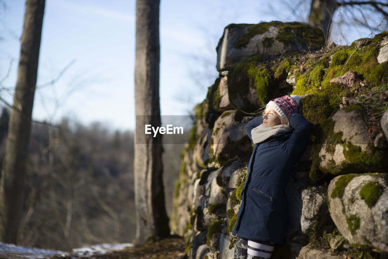 Side view of woman leaning on rocks