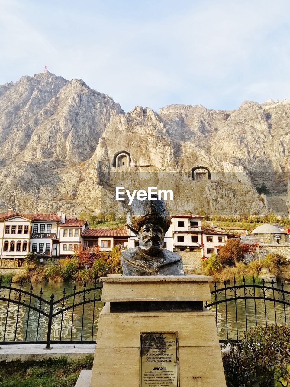 Statue against building and mountains against sky