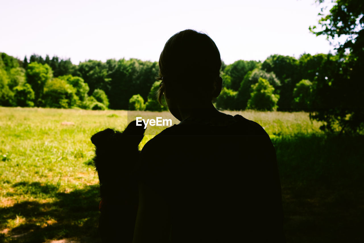 REAR VIEW OF MAN STANDING ON FIELD AGAINST SKY