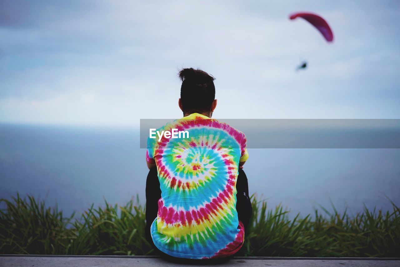 Rear view of man looking at sea against sky