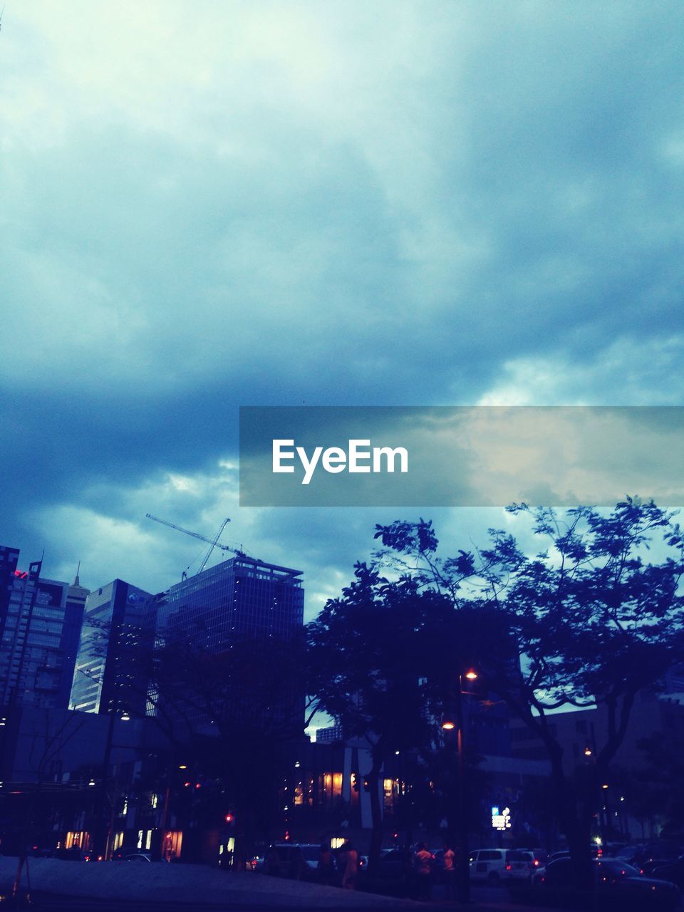 VIEW OF CITY BUILDINGS AGAINST CLOUDY SKY