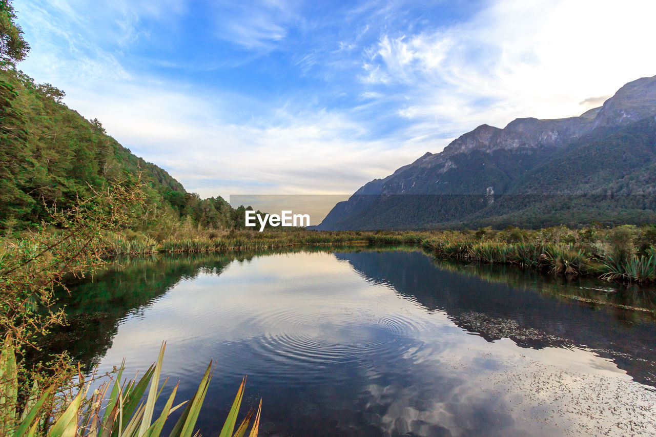 Scenic view of lake by mountains against sky