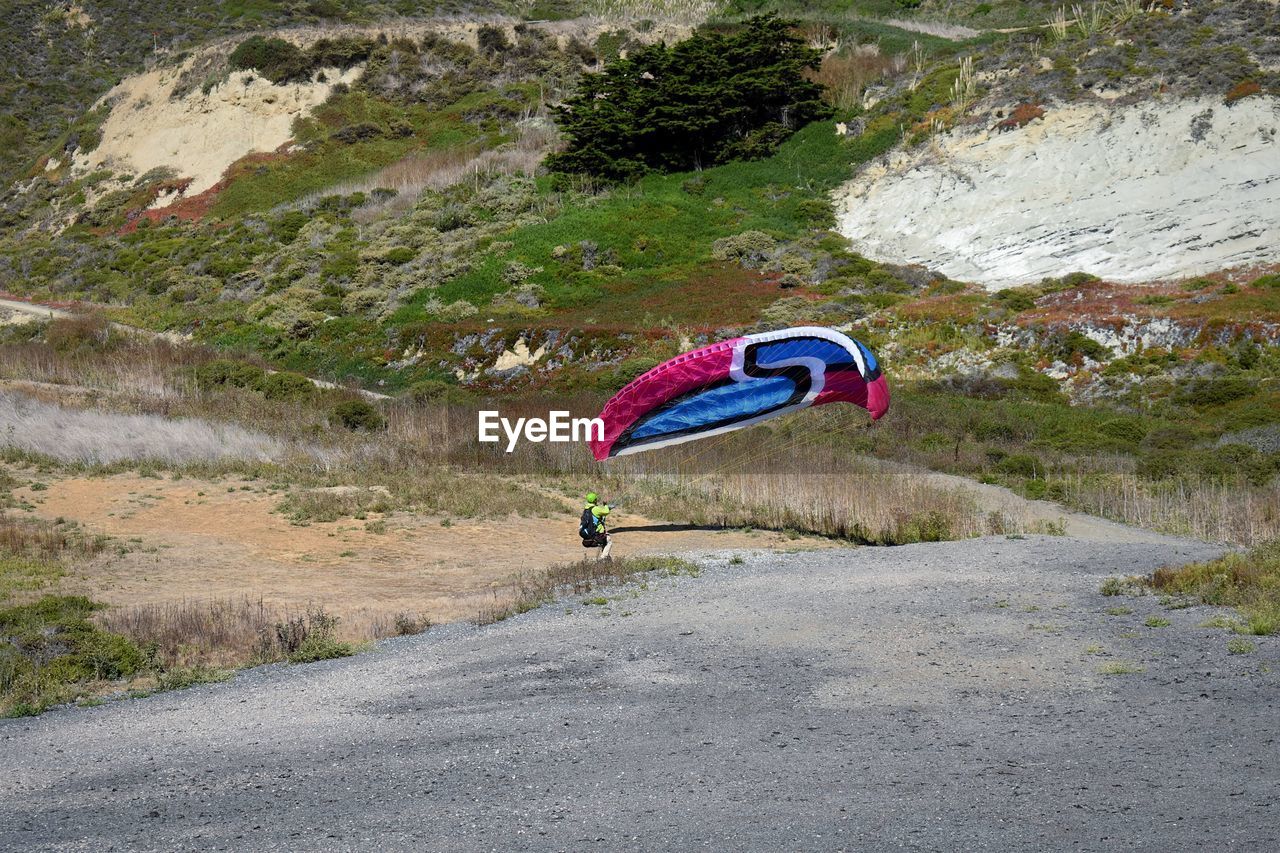 MAN PARAGLIDING OVER ROAD