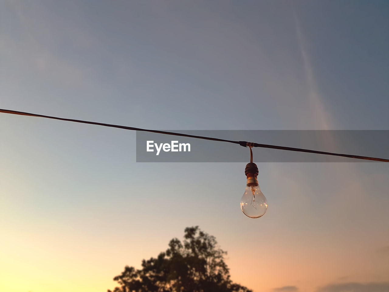 Low angle view of light bulb against sky during sunset