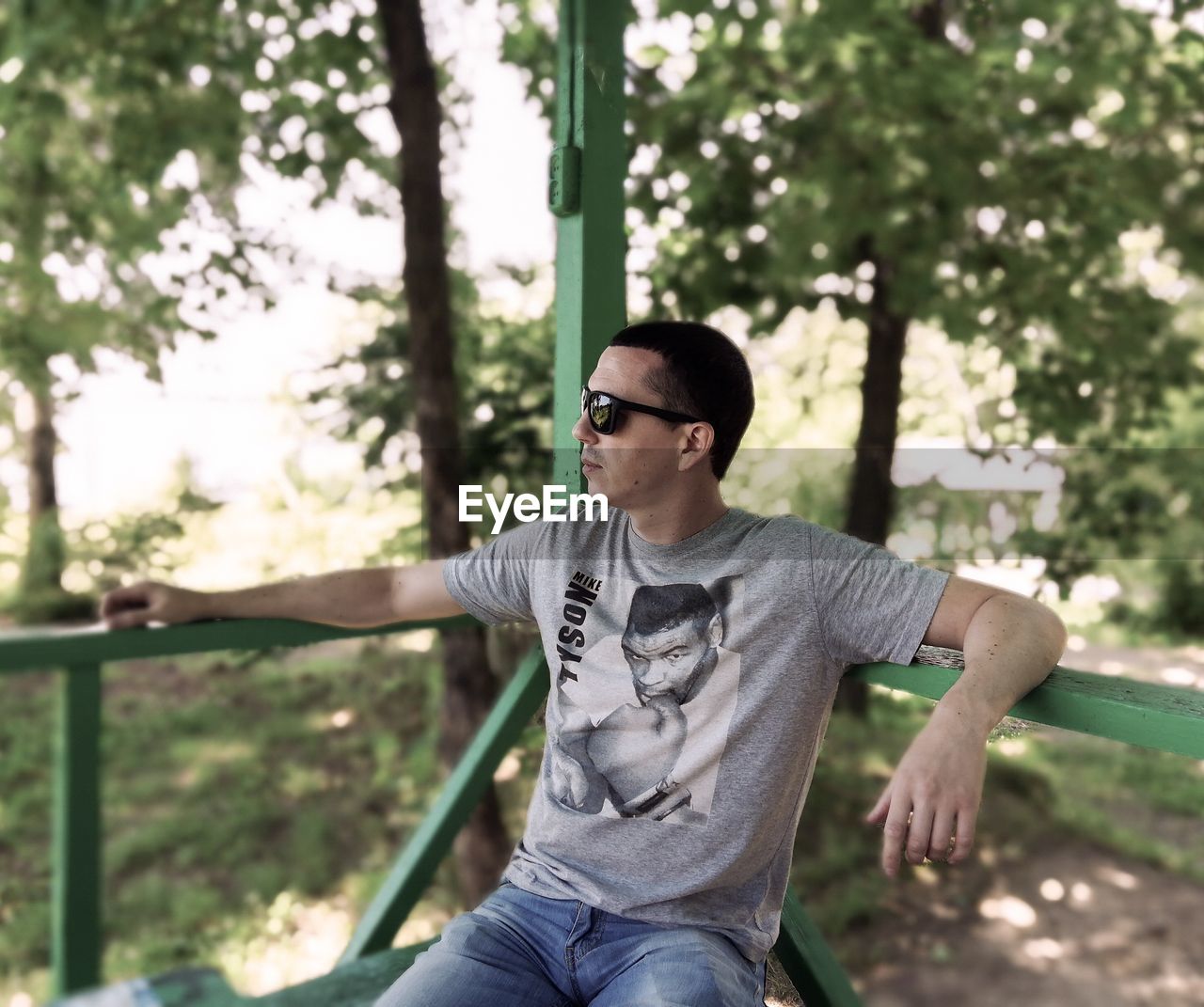 Man wearing sunglasses while sitting against trees