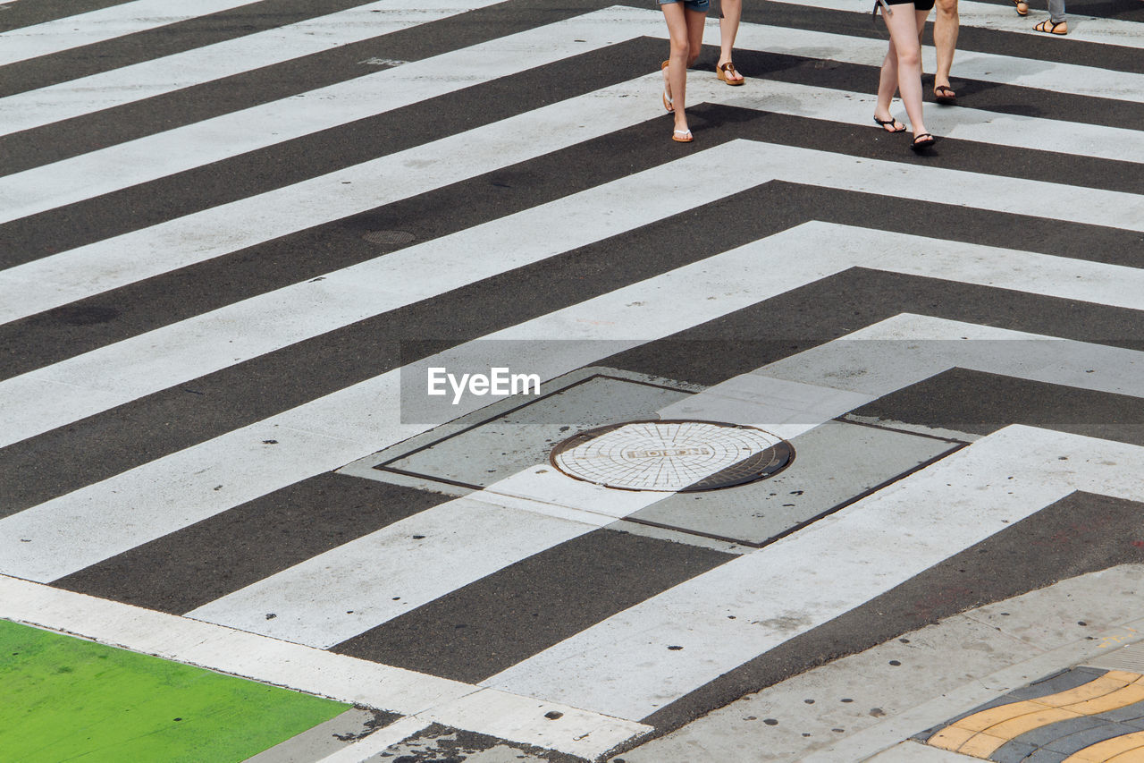 Low section of people walking on zebra crossing