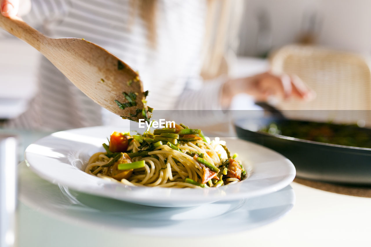 Young woman serving vegan pasta dish