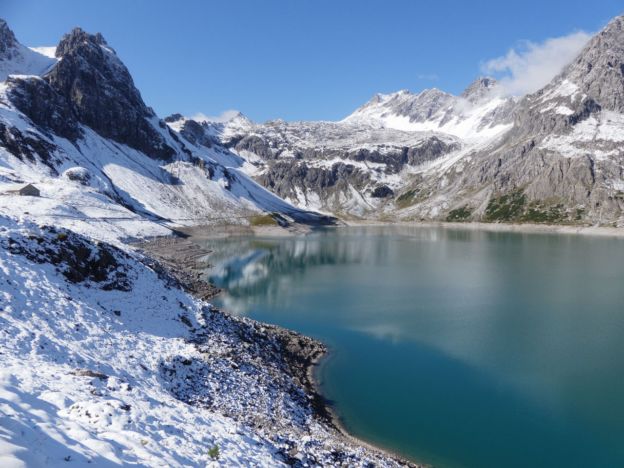 Scenic view of lake by snowcapped mountains against sky