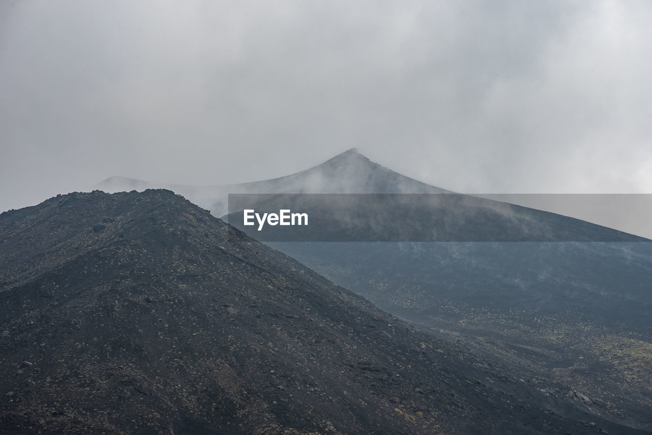 Smoke emitting from mount etna in sky amidst volcanic landscape