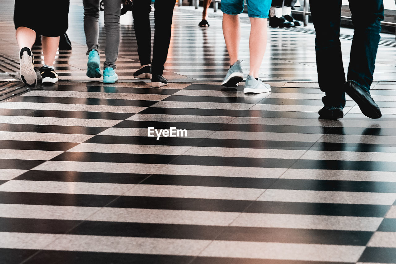 Low section of people walking on tiled floor