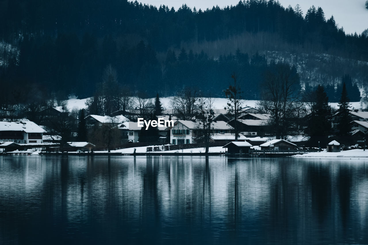 SCENIC VIEW OF LAKE BY TREES AGAINST BUILDINGS DURING WINTER