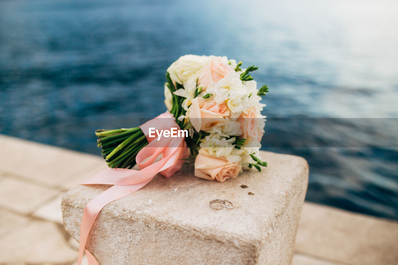 Close-up of rose bouquet and rings on rock