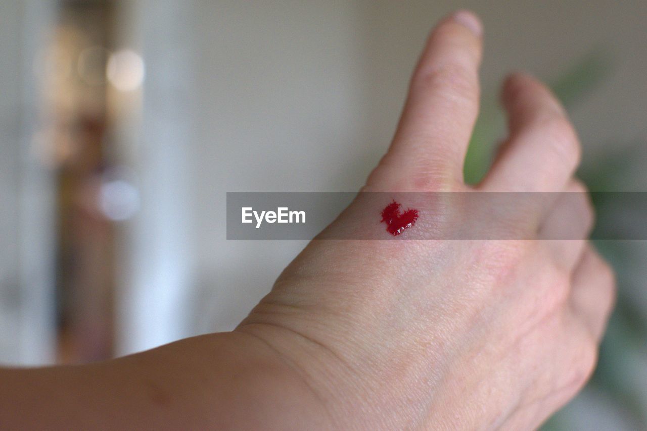 Close-up of heart shaped blood on person hand