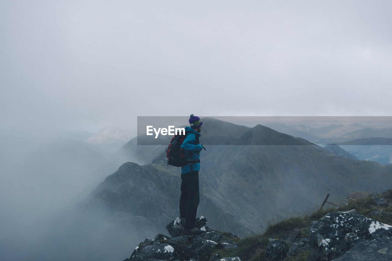 Man standing on mountain during foggy weather