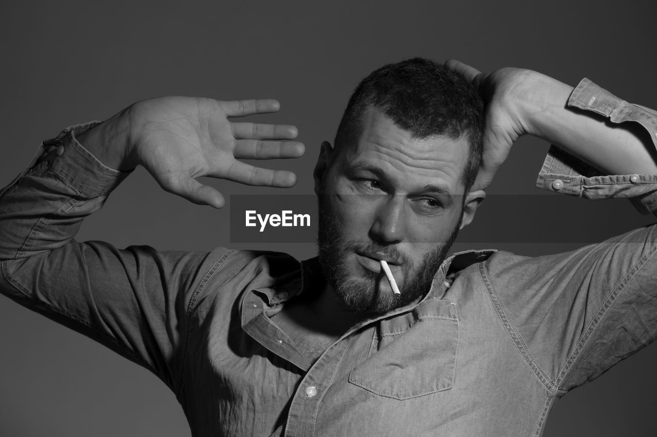 Close-up of man smoking cigarette against gray background