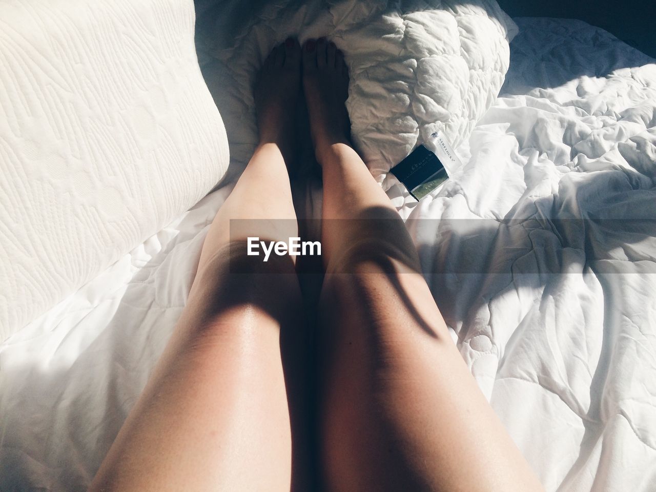 Sunlight falling on woman legs in bed