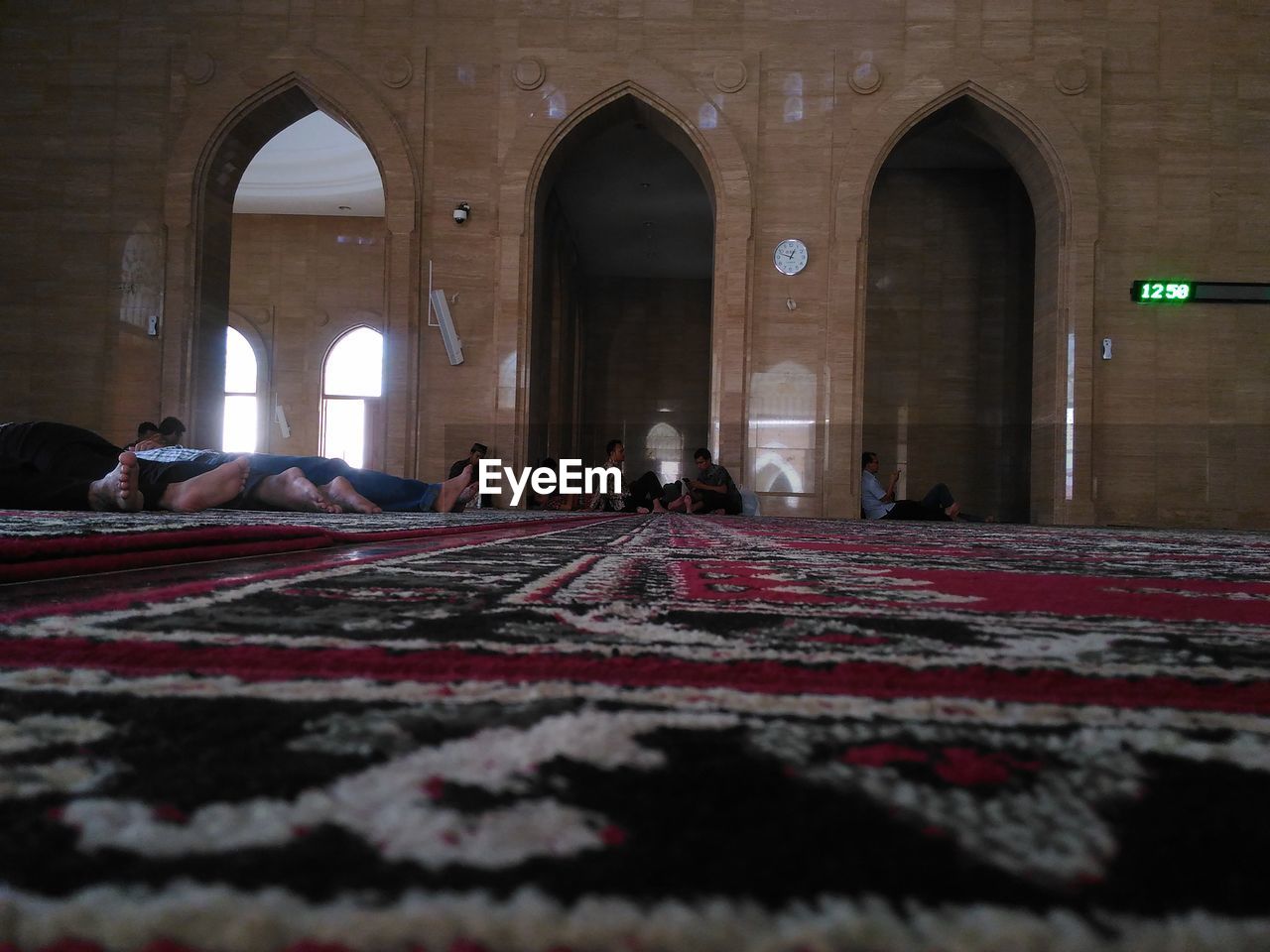 People relaxing on rug at mosque