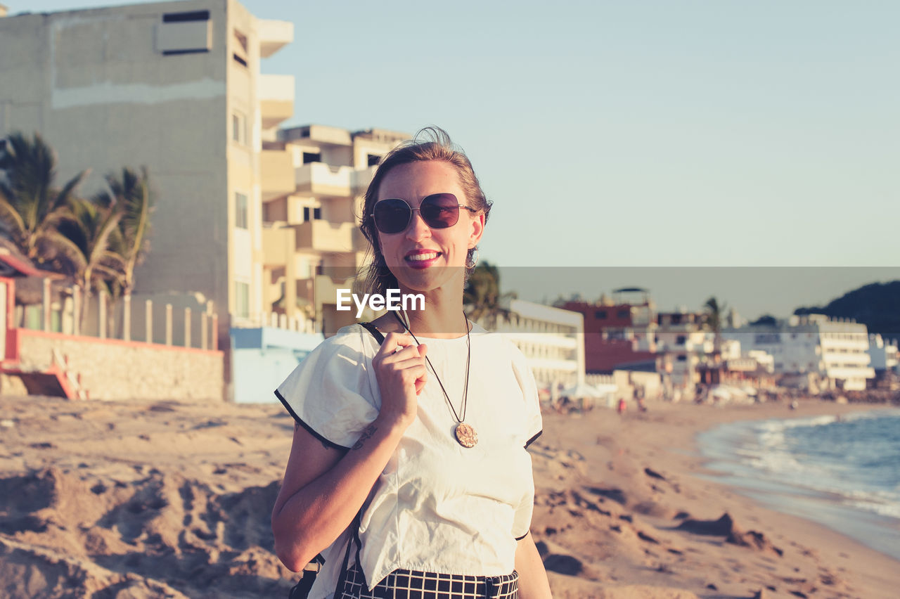 Young woman smiling at the beach at sunset