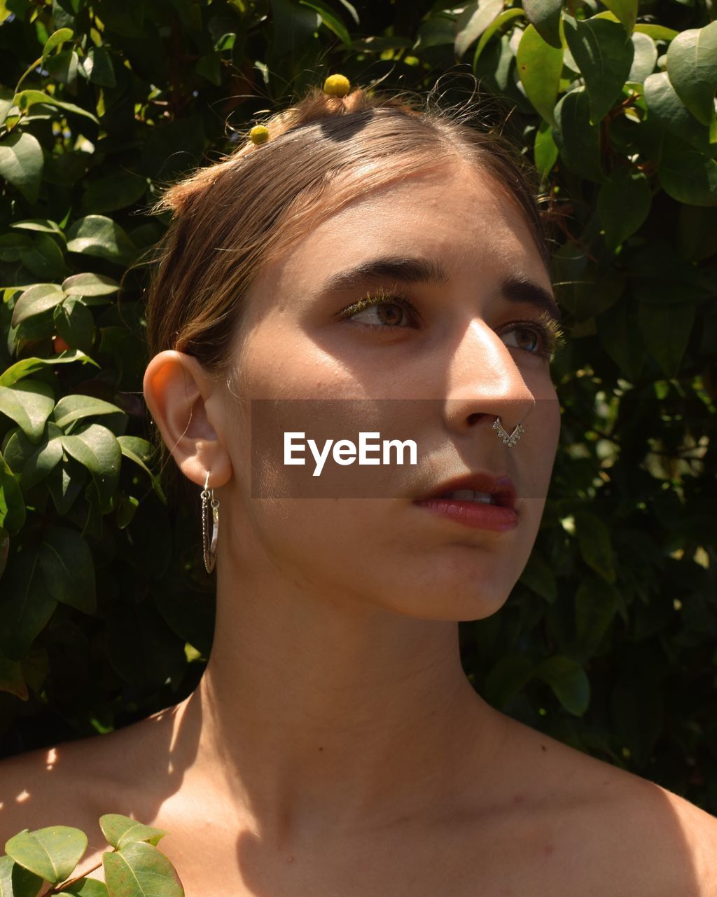 Close-up of thoughtful beautiful woman standing by plants at park